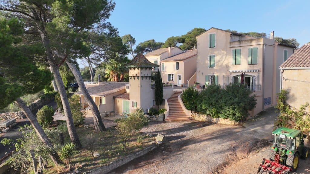 Gîte de charme en Provence avec tour et grand jardin Maisons provençales aux volets verts avec tour et escalier sous les pins, un tracteur vert au premier plan.